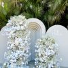 a white arch with flowers and a sign